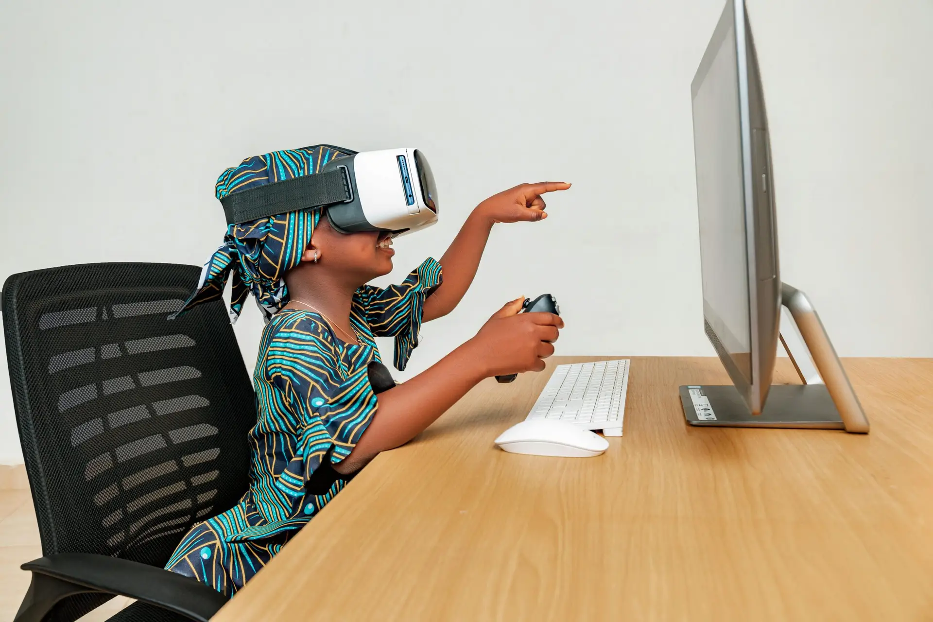 Young child using a VR headset and controller at a desk, engaging with technology.